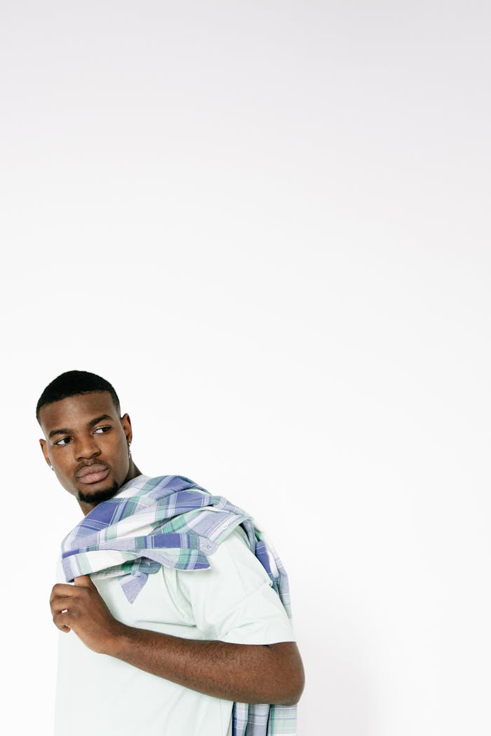 Young black man in casual attire looking back with white background and copy space.