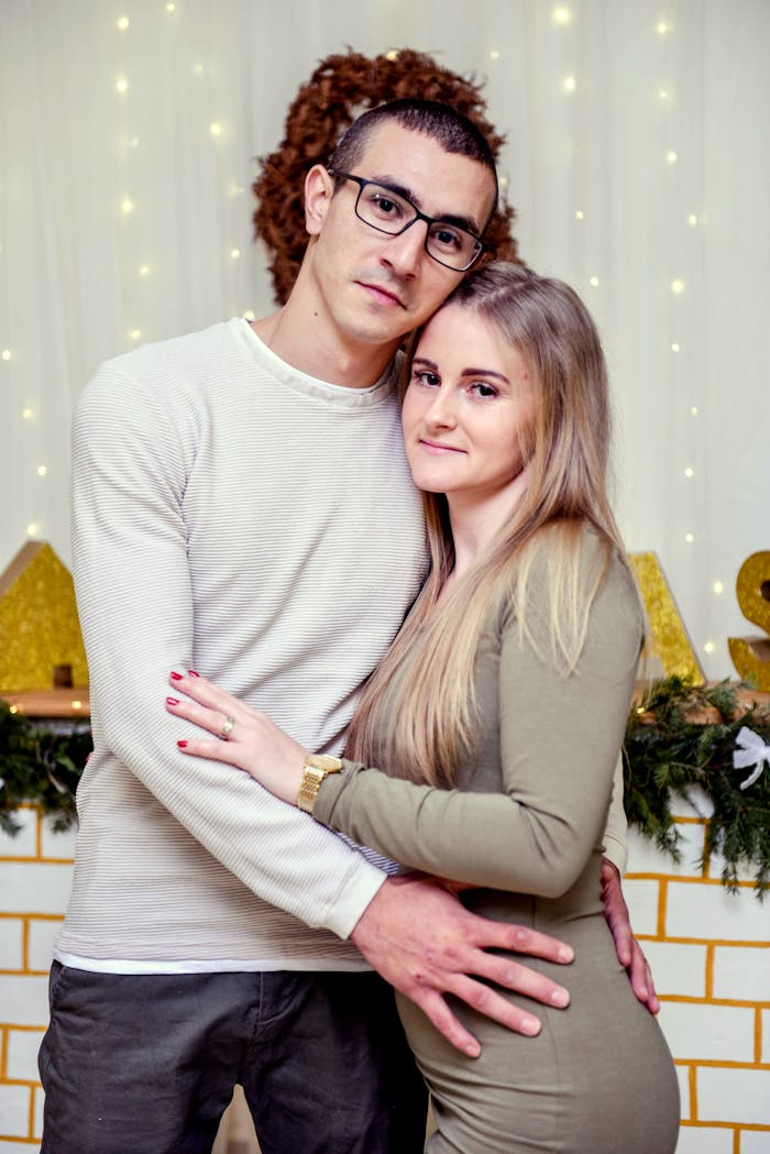 A couple sharing a warm embrace in a decorated room, exuding holiday cheer.